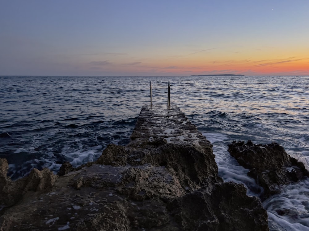 a long pier extending into the ocean at sunset