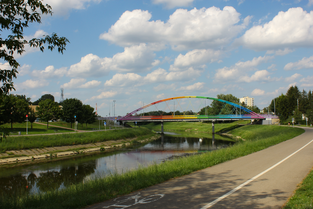 a rainbow colored bridge over a small river