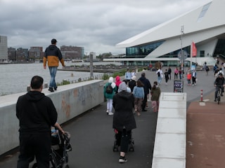 A diverse group of professionals walking and biking to work in an urban setting with green spaces.