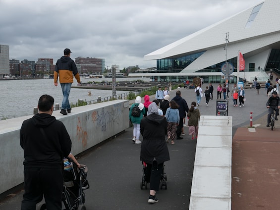 A diverse group of professionals walking and biking to work in an urban setting with green spaces.