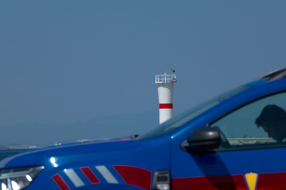 a blue truck parked next to a light house