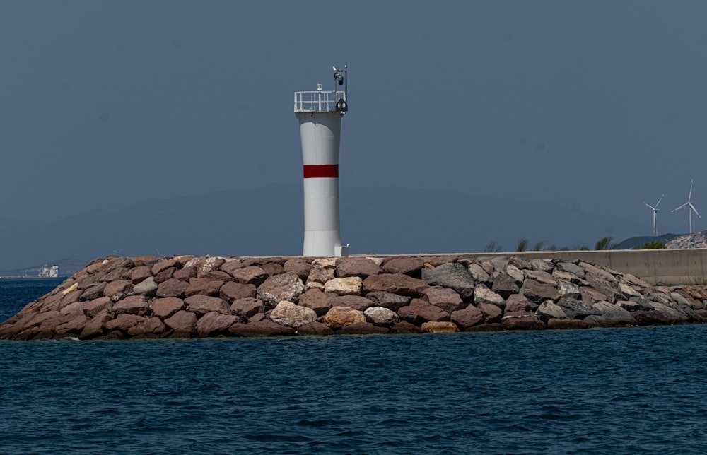 a red and white lighthouse sitting on top of a rock wall