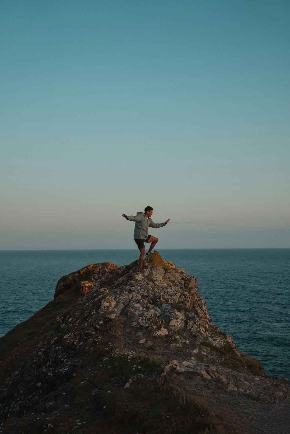 a man sitting on top of a rock near the ocean