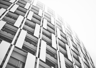 An architectural blueprint overlaying a modern building facade in monochrome tones.
