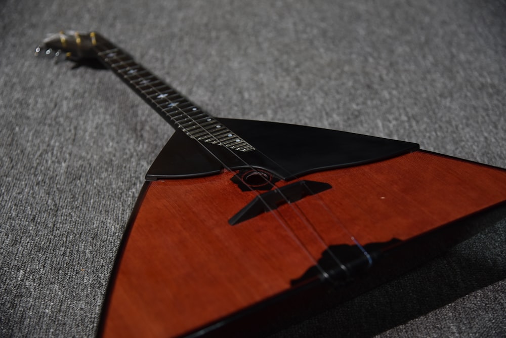 uma guitarra de madeira sentada em cima de um tapete cinza