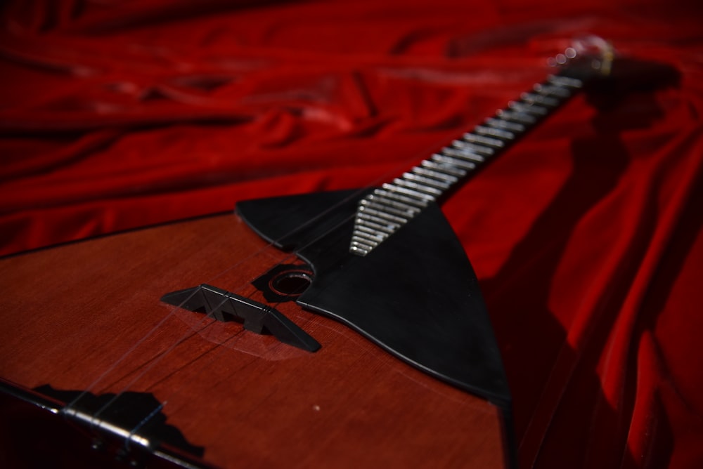 a close up of a guitar on a red sheet