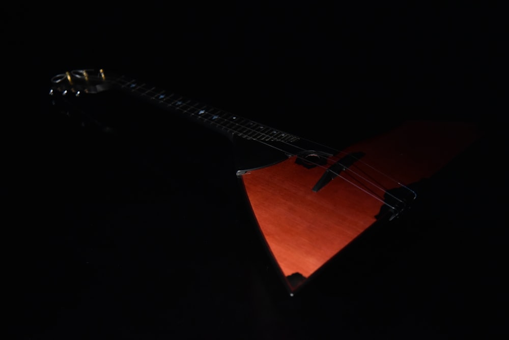 a red guitar sitting on top of a black table