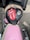 A motorcycle seat cover features a prominent red and white logo of a tongue and lips, the phrase 'ROCK N ROLL,' and an illustration of an eagle wearing sunglasses. The seat sits atop a pink motorcycle with chrome handlebars, parked on an asphalt surface.