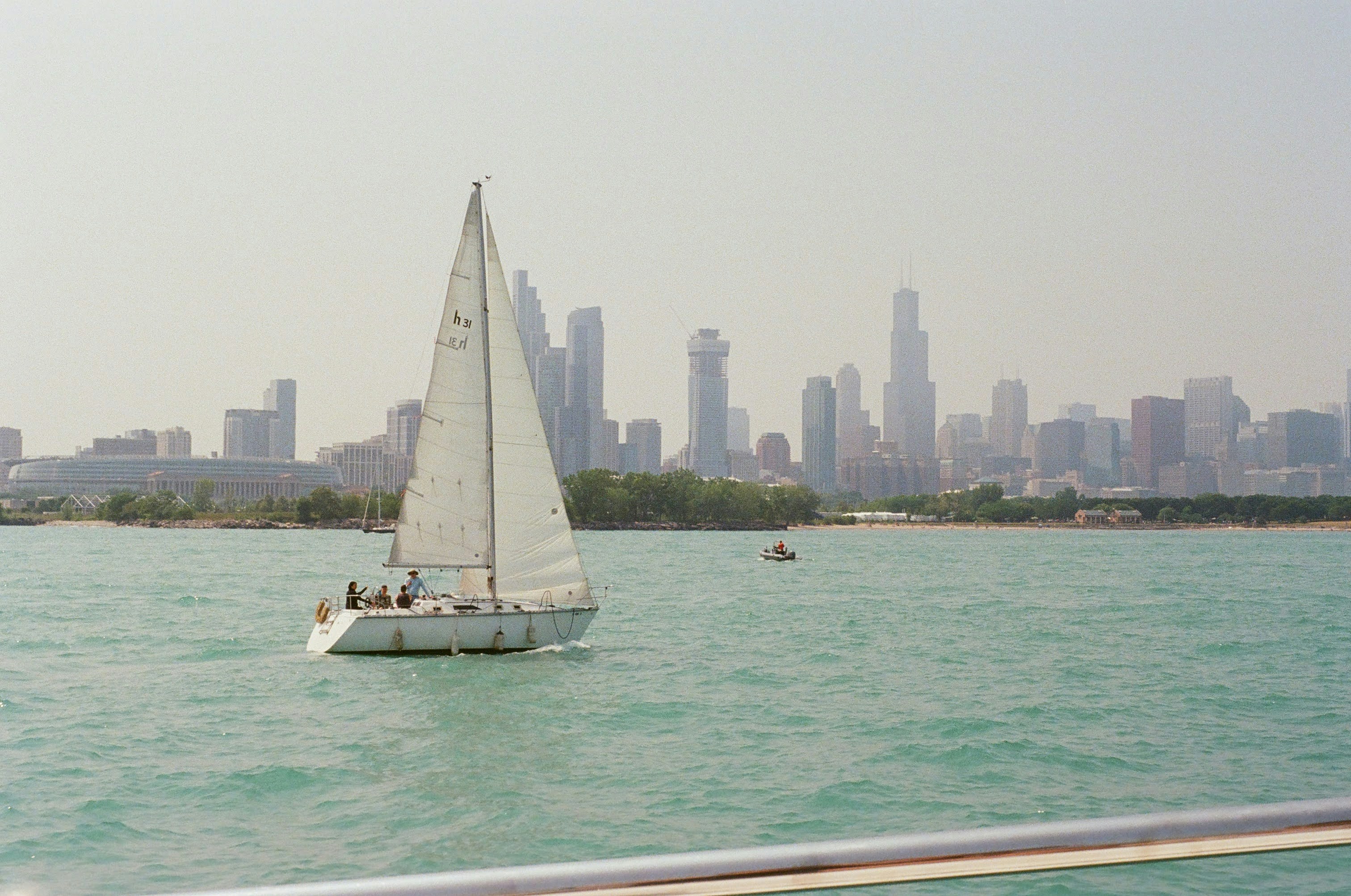 a sailboat in the water with a city in the background