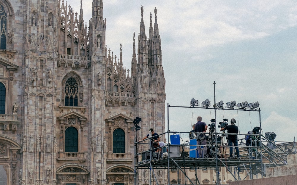 a group of people standing on a scaffold in front of a cathedral