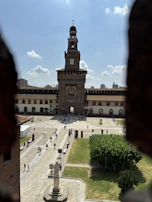 A historic castle courtyard of Castello Sforzesco filled with visitors.