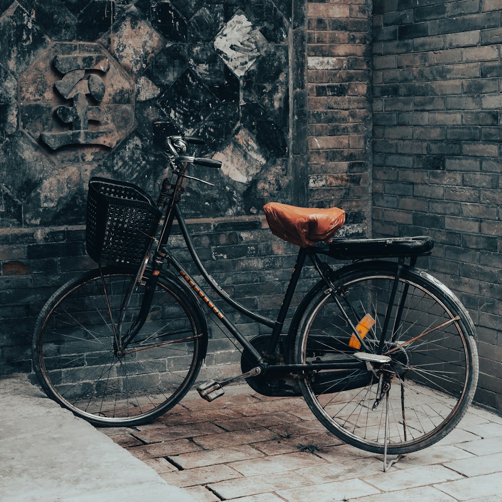 a bicycle parked next to a brick wall