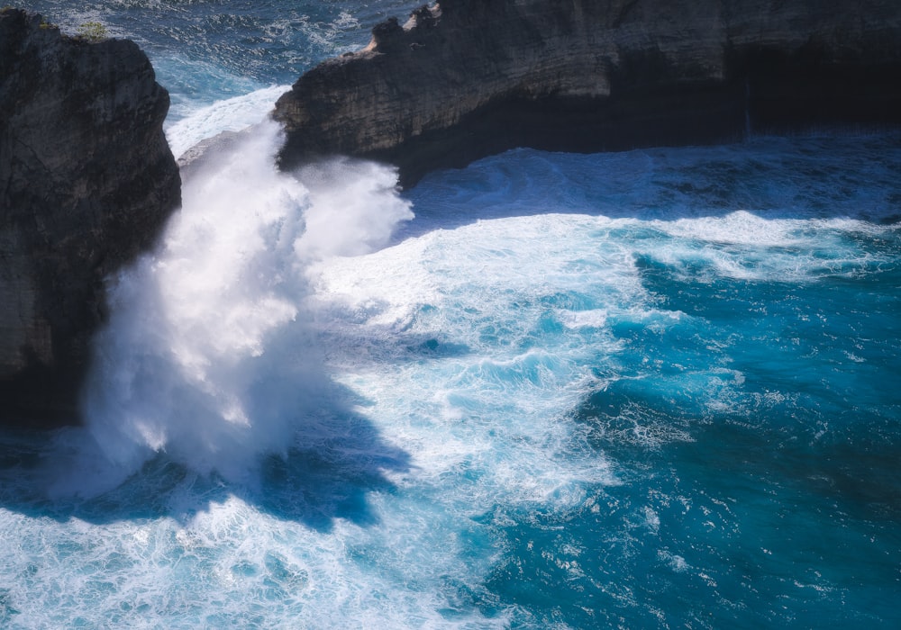 a large wave crashes into the rocks near the ocean