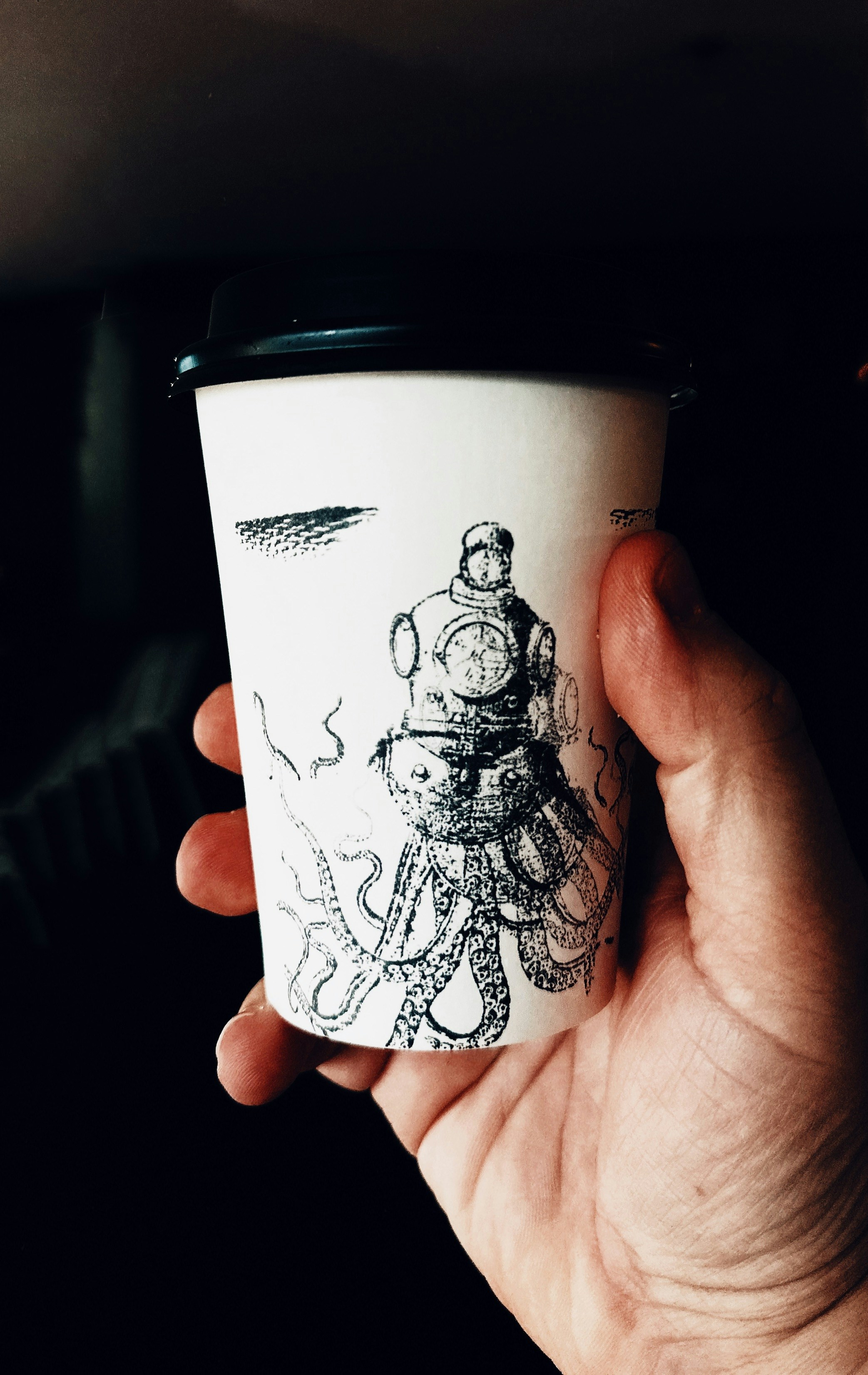 una mano che tiene una tazza di caffè con un disegno su di essa
