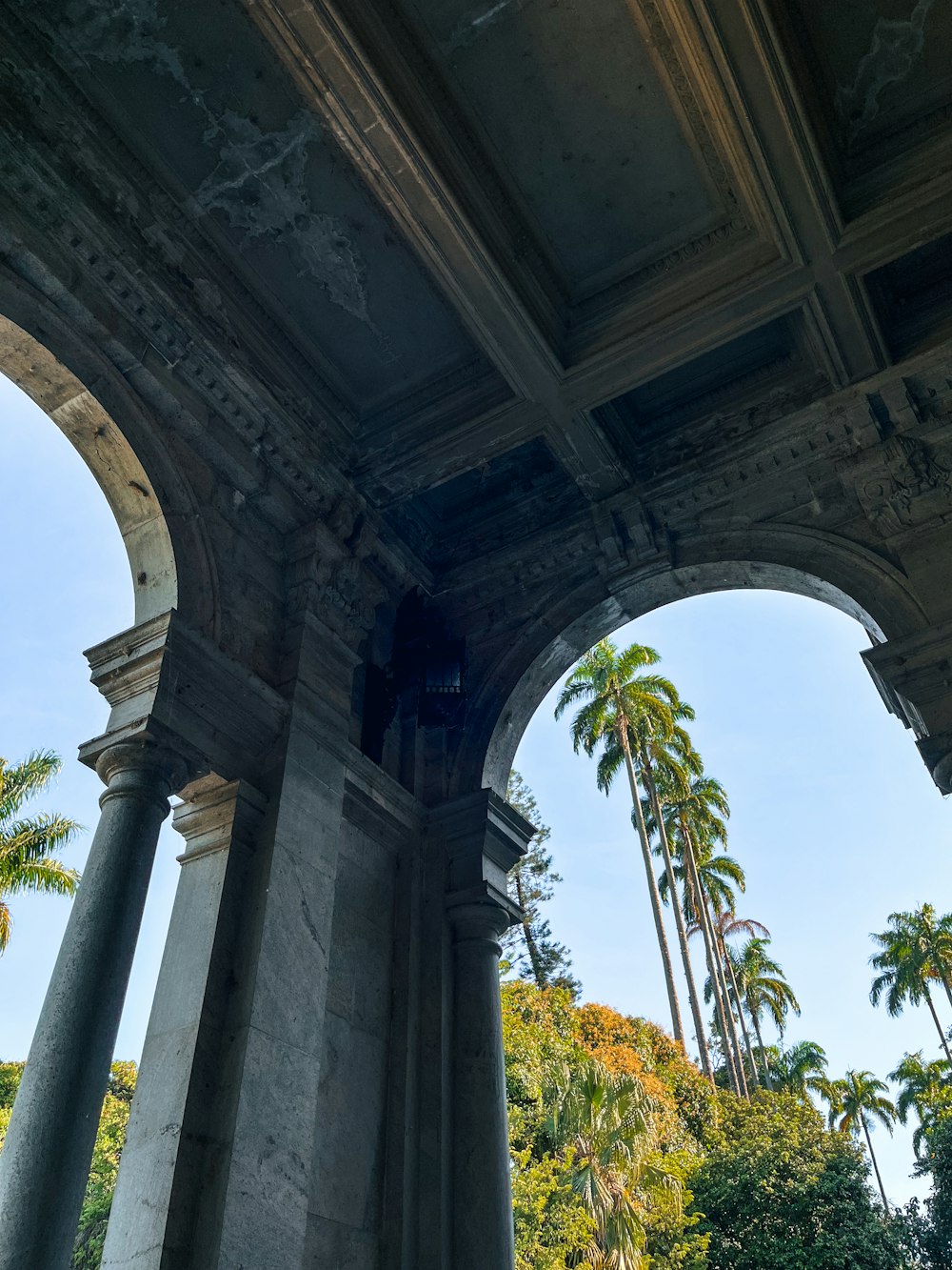 an old building with columns and palm trees in the background