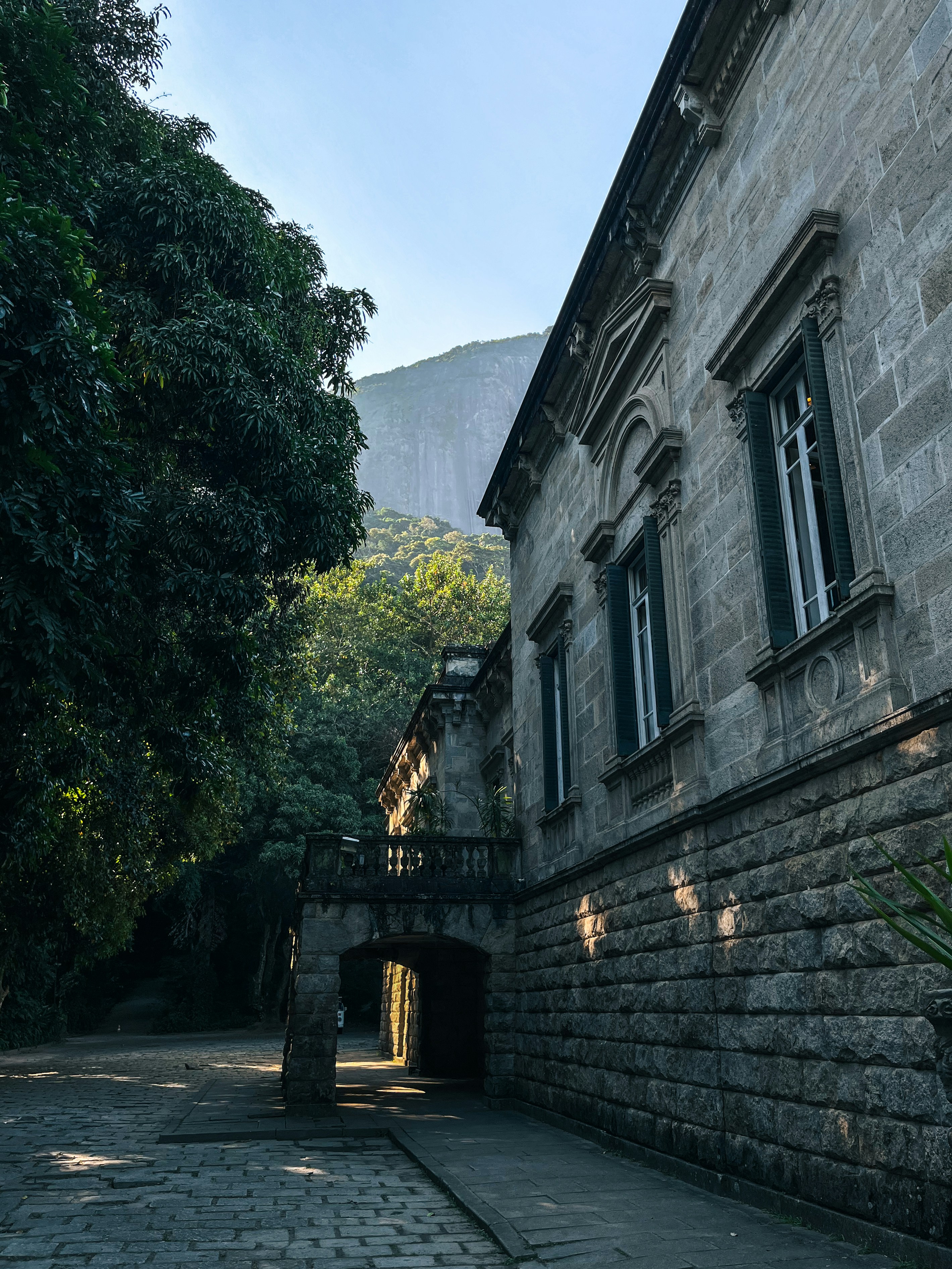 a stone building with green shutters on the windows