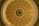 A detailed view of a circular, ornate dome ceiling with intricate architectural designs. The center features a large star with letters spelling out 'TEXAS' around it. The structure is decorated with moldings and panels, painted in shades of beige and gold.