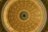 A detailed view of a circular, ornate dome ceiling with intricate architectural designs. The center features a large star with letters spelling out 'TEXAS' around it. The structure is decorated with moldings and panels, painted in shades of beige and gold.