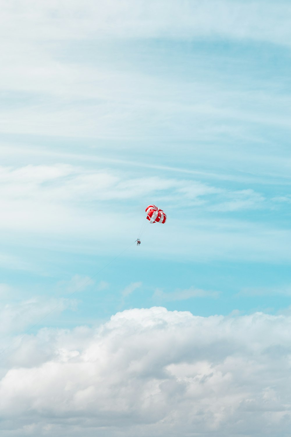 um par de pipas voando através de um céu azul nublado