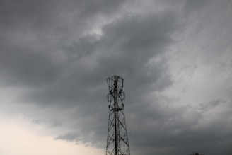 Close-up of a rugged IoT sensor transmitting data through a satellite network under stormy skies.