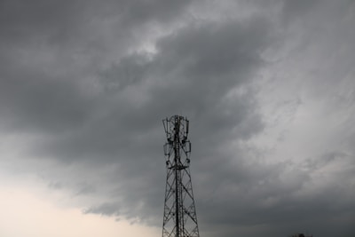 A cell tower stands against a backdrop of dark, cloudy skies, suggesting an impending storm.