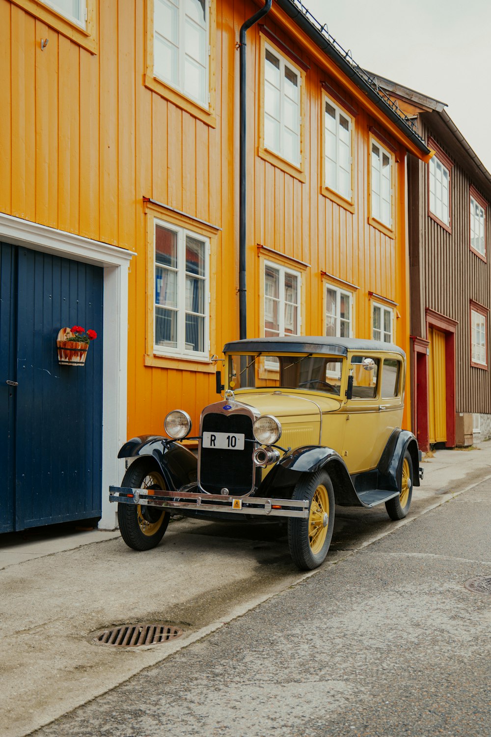 an old yellow car parked in front of a building