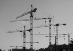 a black and white photo of construction cranes