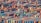Numerous shipping containers are stacked in an organized manner, filling the entire frame. They vary in colors, such as red, blue, green, and orange, creating a vibrant and busy atmosphere. A crane is seen among the containers, indicating an industrial setting.