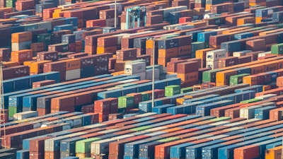 A busy logistics warehouse with crates and shipping containers being organized for global transport.