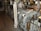 A well-maintained industrial or mechanical room featuring a variety of metal machinery and pipes. There is a large valve wheel and various gauges and switches, suggesting it may be part of a ship's engine room or an industrial plant.