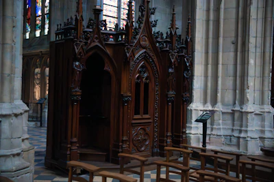 A priest hearing confession in a classic confessional booth with soft lighting.