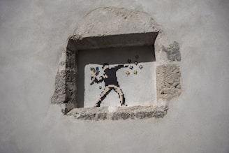 A pixel art mural depicting a figure in a throwing stance, reminiscent of a protester, but instead of a projectile, colorful flowers emerge from the hand. The artwork is situated within a rough-hewn stone niche on a plain wall.