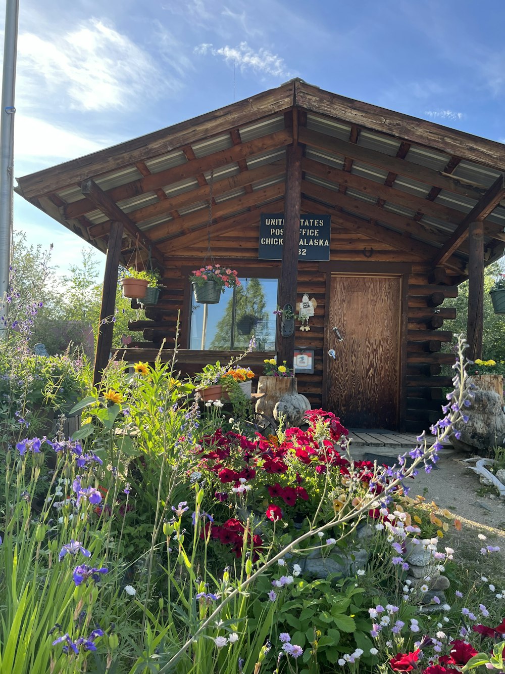 un bâtiment en bois avec une porte en bois entourée de fleurs