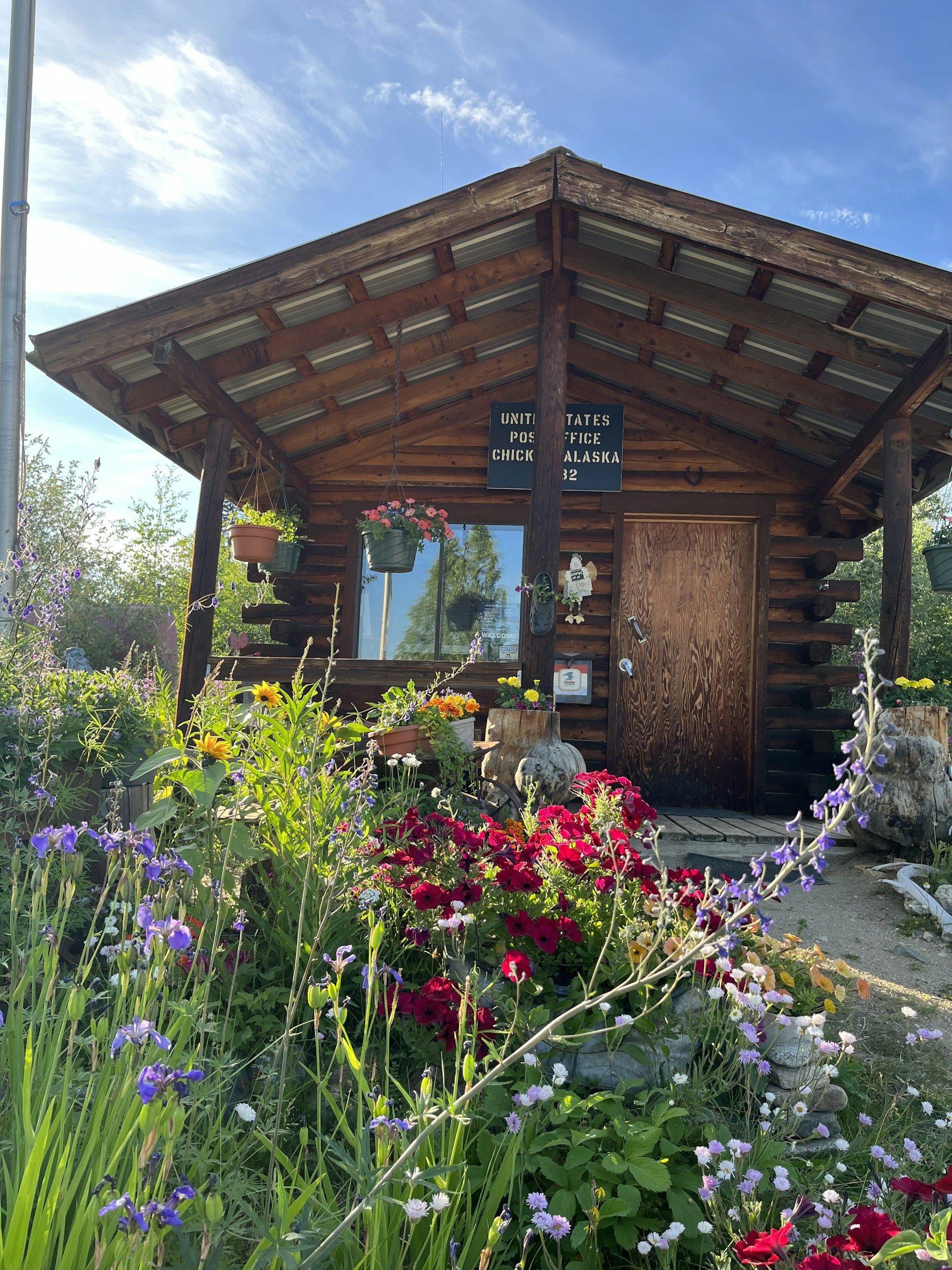 a wooden building with a wooden door surrounded by flowers