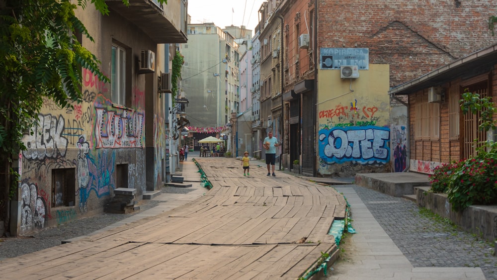 a person walking down a street with graffiti on the walls