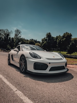 Side profile of a white Porsche 911 sports car on a coastal road.