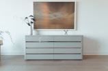 A modern dresser with clean lines and elegant handles, set against a warm-toned wall.