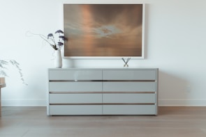 A modern dresser with clean lines and elegant handles, set against a warm-toned wall.