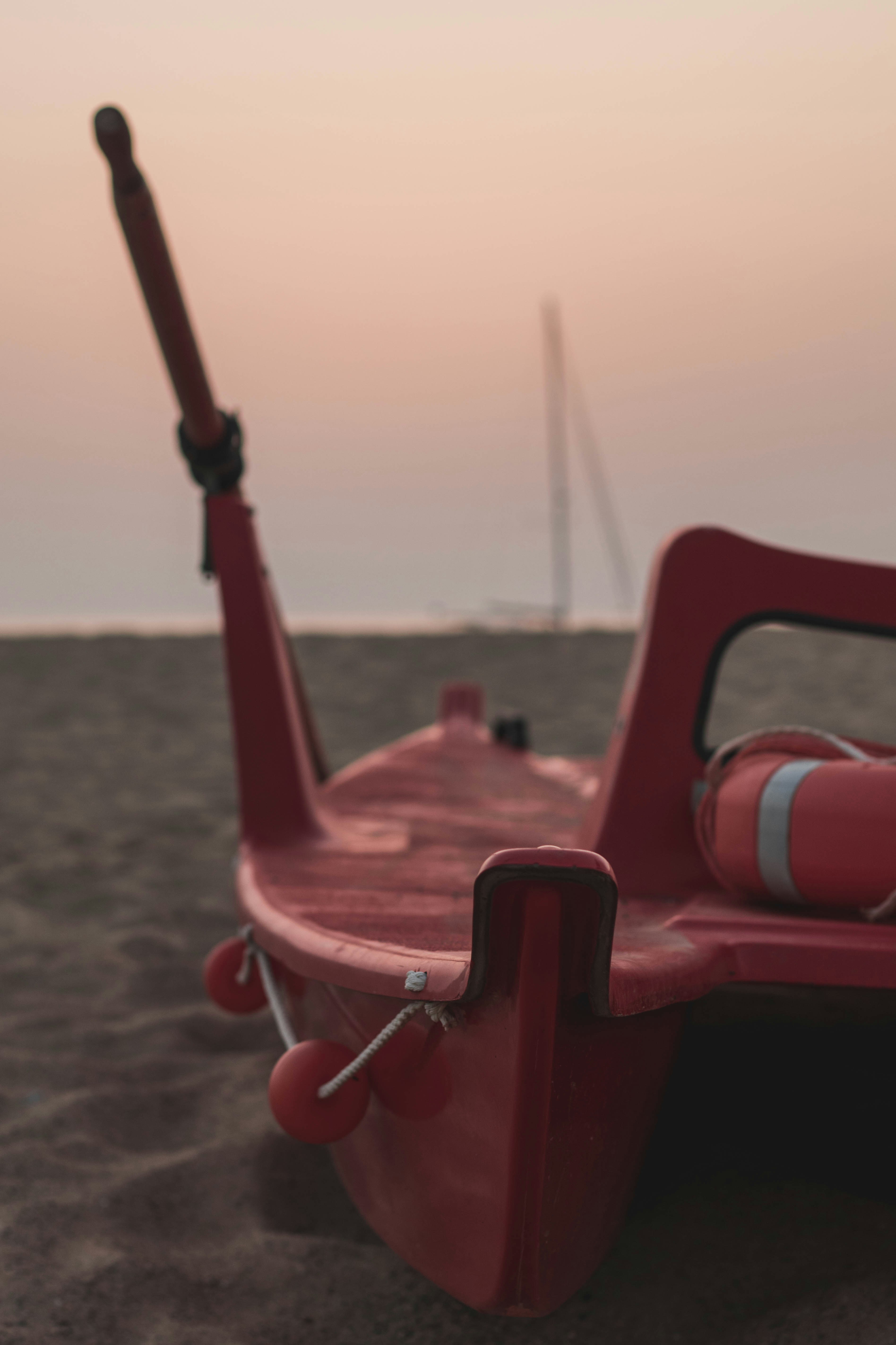 a red boat sitting on top of a sandy beach