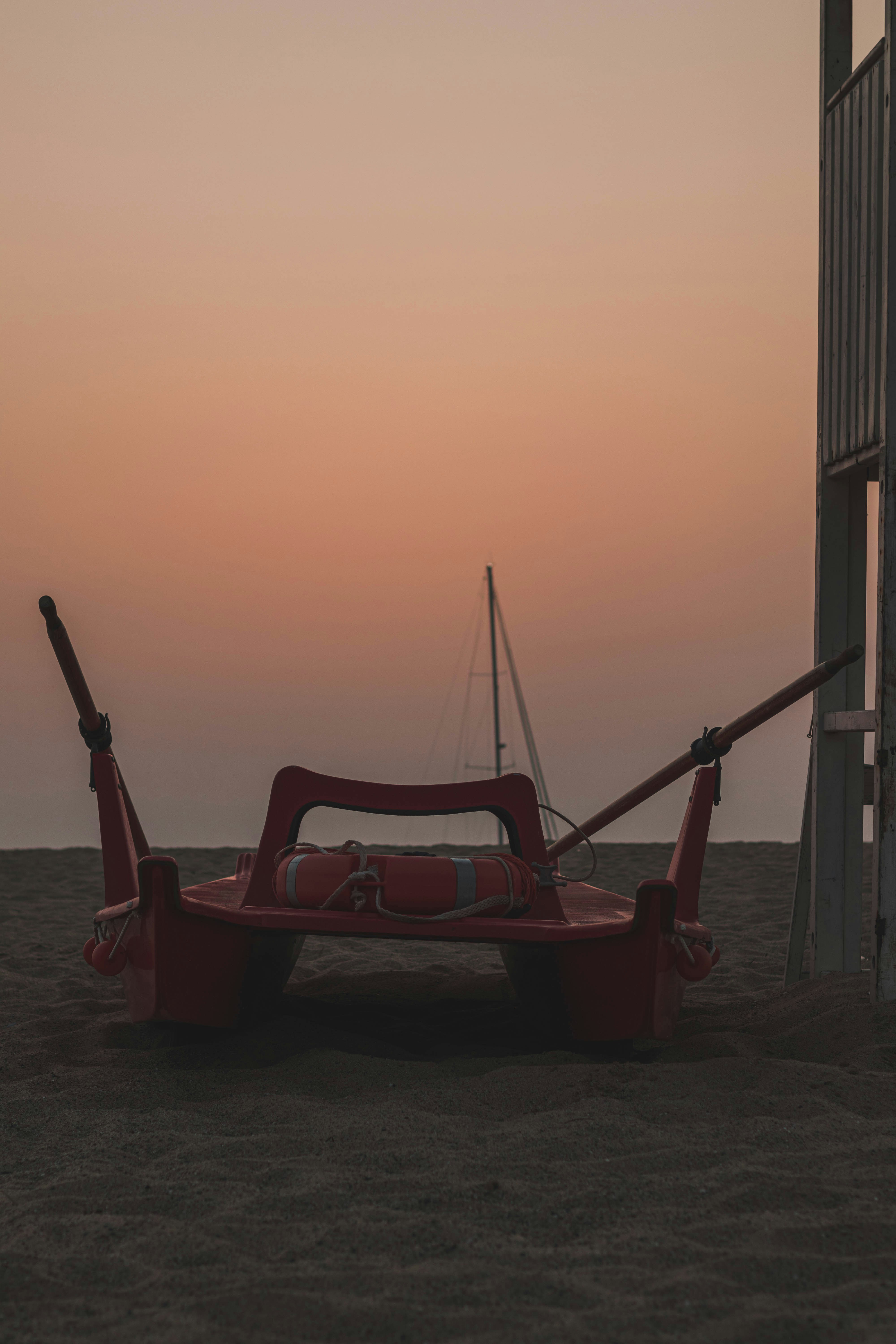 a red boat sitting on top of a sandy beach