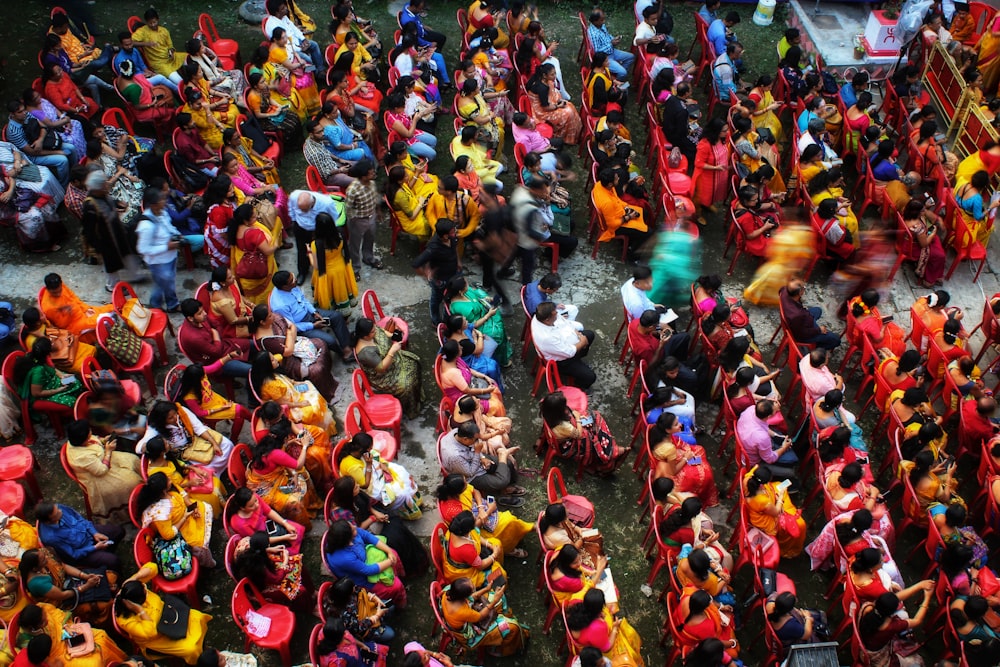 a large group of people sitting on top of red chairs