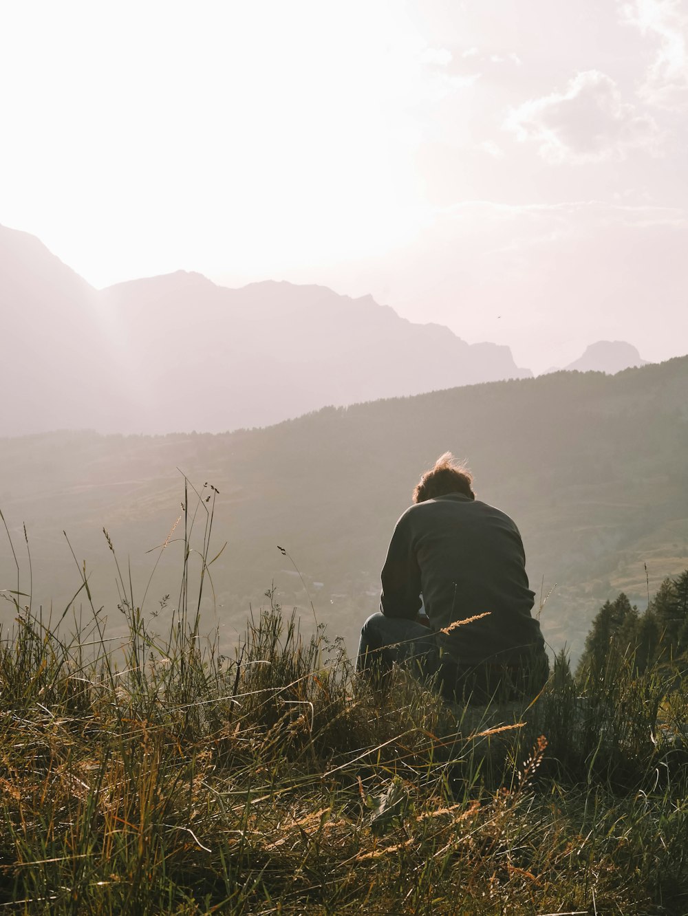 a man sitting on top of a lush green hillside