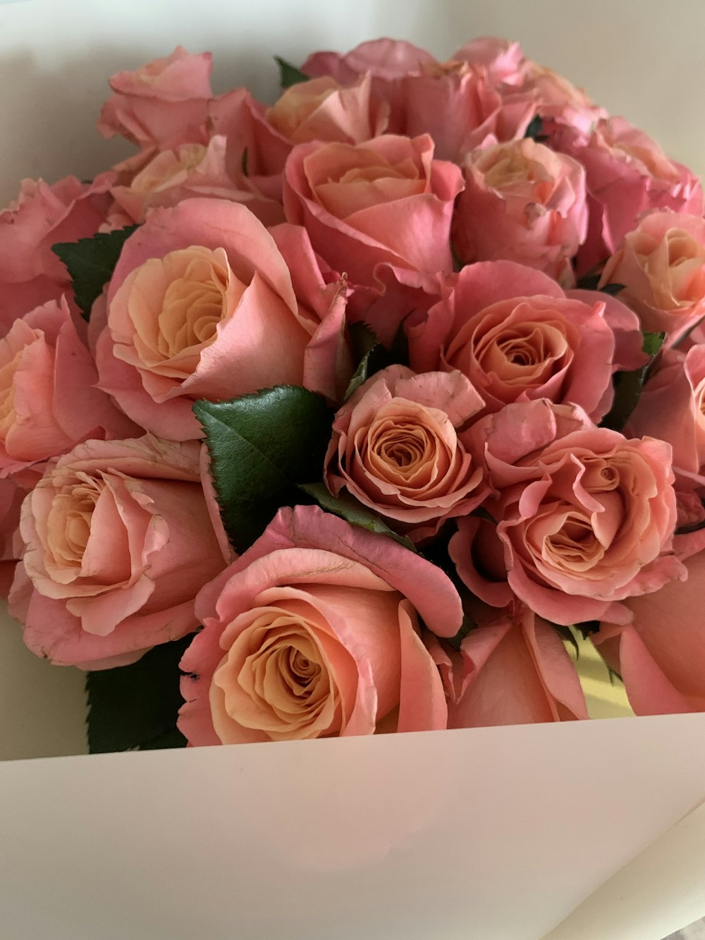 a bouquet of pink roses in a white box