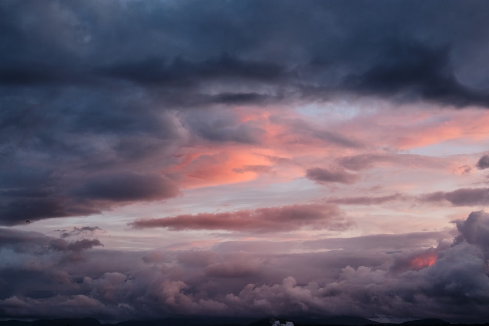 the sky is filled with dark clouds as the sun sets