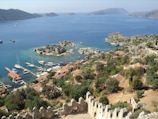 A panoramic view of a coastal village with boats docked and mountains in the background.