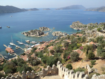 A panoramic view of a coastal village with boats docked and mountains in the background.
