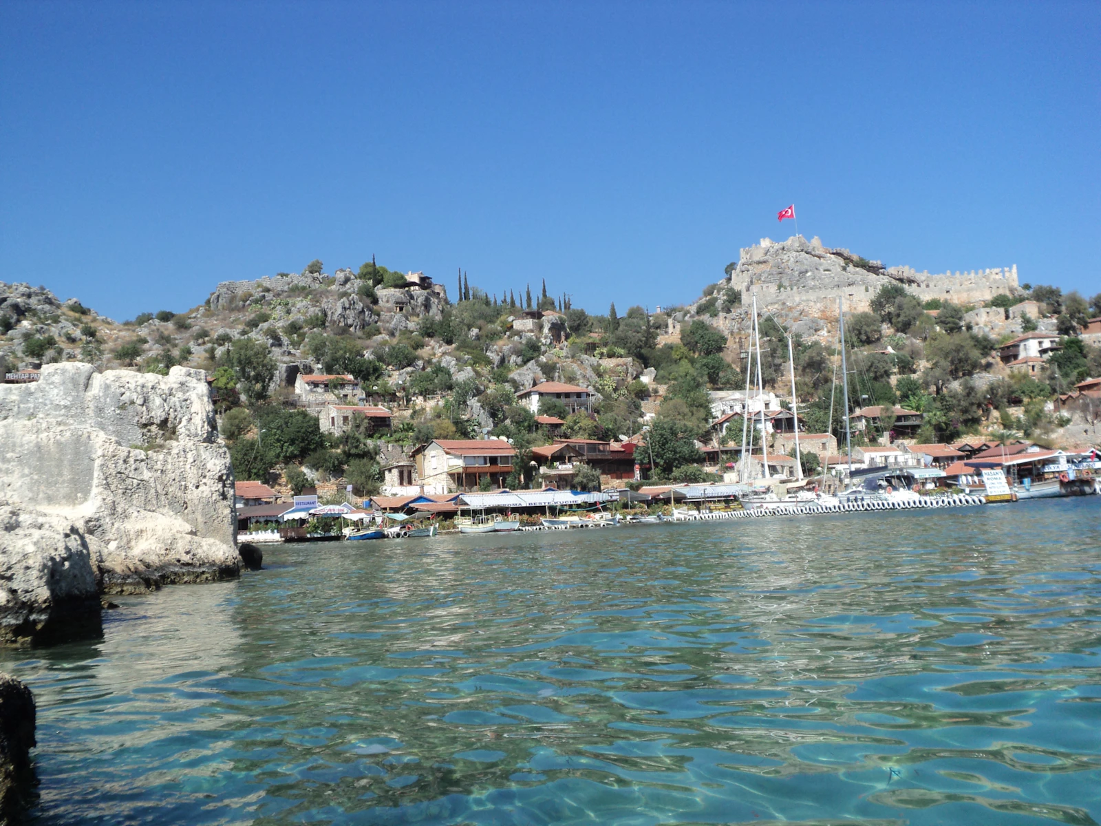 Boats in the bay below a castle on the hill near Kaş