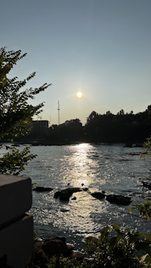 A serene riverside temple at sunset with gentle flowing water and soft golden light.