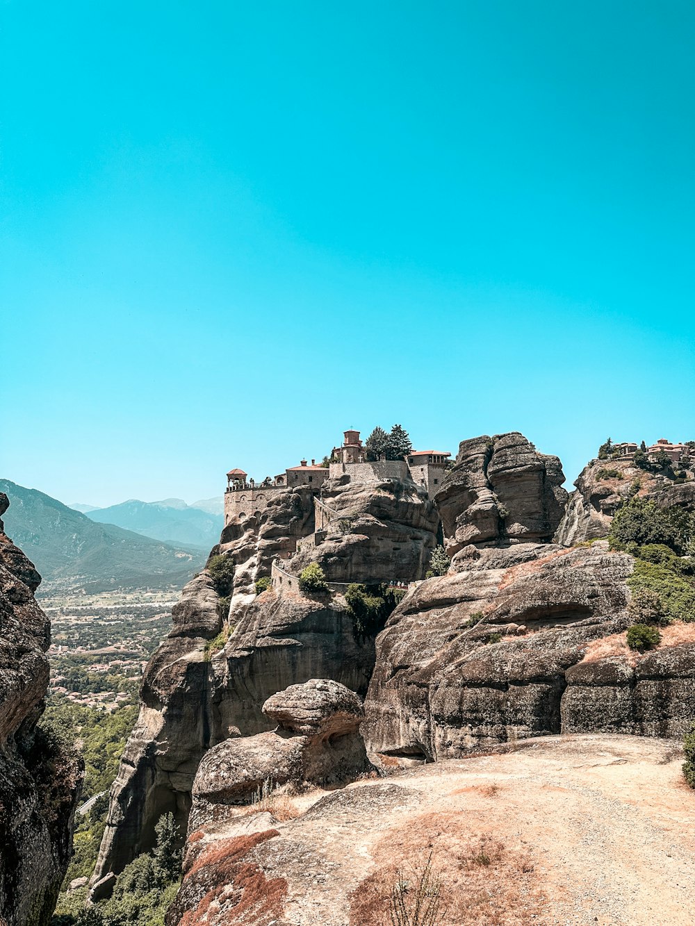 a man standing on top of a mountain next to a lush green forest