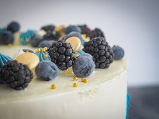 Close-up of an elegant French cake decorated with fresh berries and delicate icing in shades of chantilly and light purple.